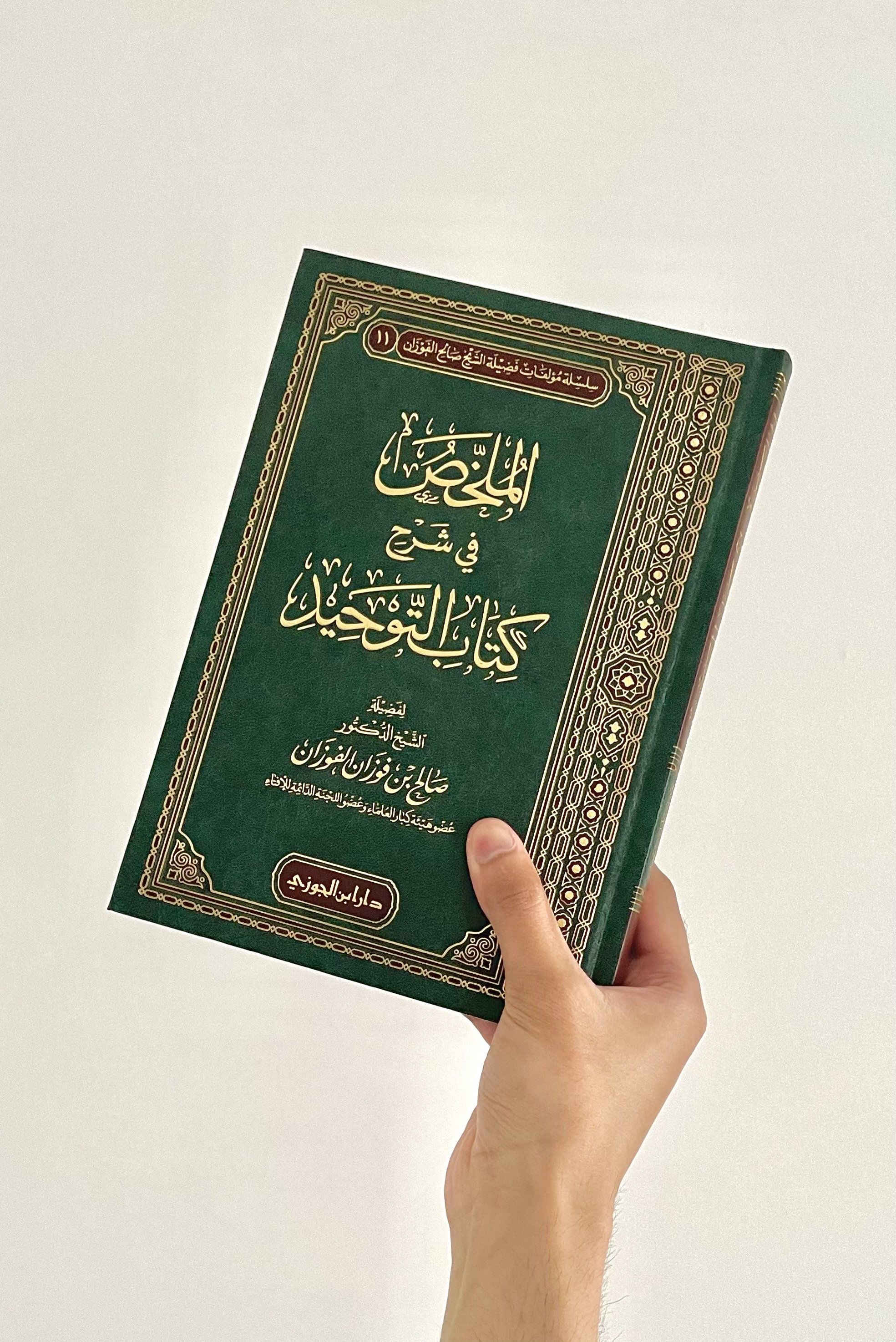 A hand holding an Islamic book